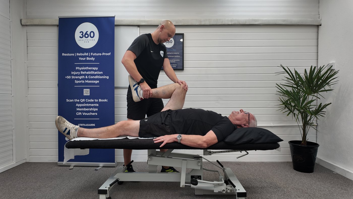 Ben supporting a client’s bent leg during hands-on injury rehabilitation